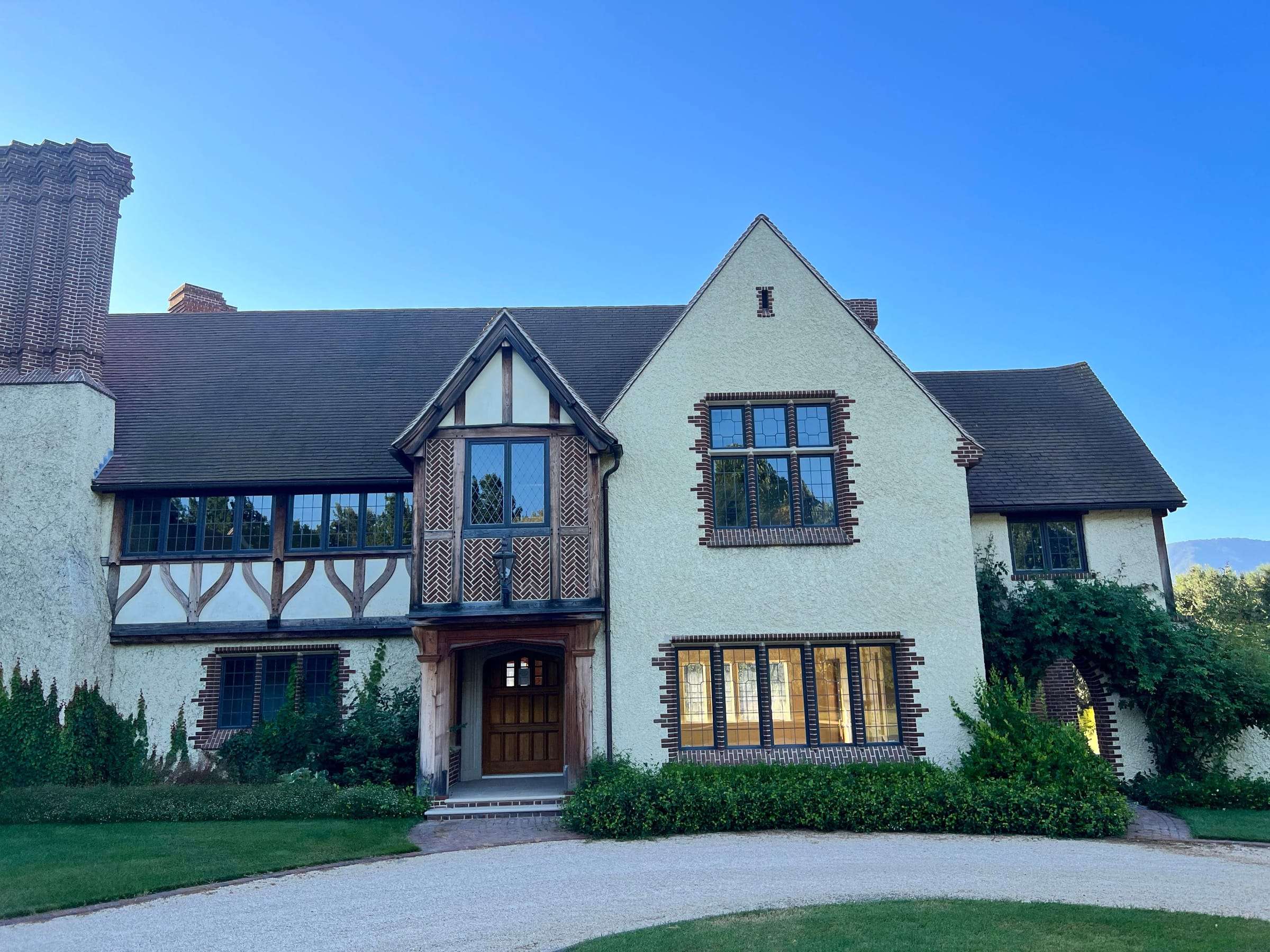 Tudor-style estate with half-timbered gables, leaded windows, and a gravel motor court